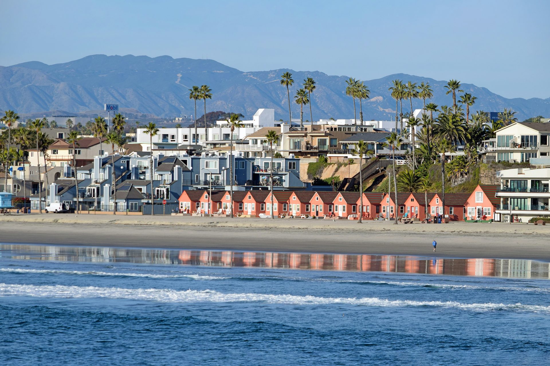 Iconic pink beach bungalows with luxury homes behind them in Oceanside